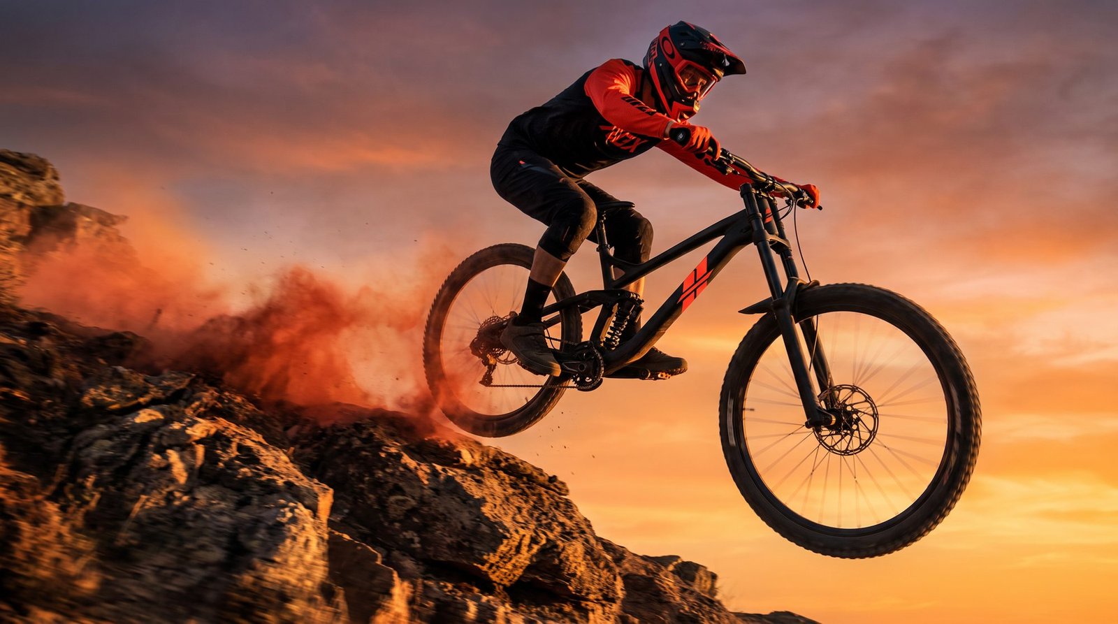 Downhill rider in mid-air on an IMPETU bike at golden hour